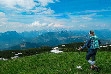 Naklejka na ściany i meble Hiker woman on top of mount Kriznik, Carinthia, border Austria Slovenia. Alpine meadow with scenic view of mountain range Karawanks, Slovenian Austrian Alps. Hiking trail Petzen, Bleiburg, Völkermarkt