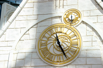 detail of the golden clock on the white brick tower wall 