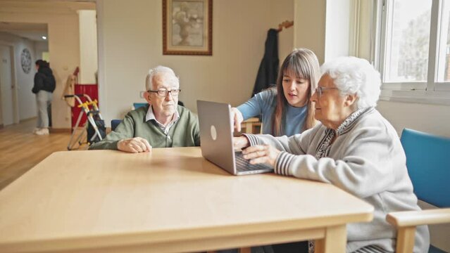 young girl teaching how to use a laptop computer to her grandparents