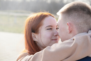 Fototapeta premium cheerful romantic couple dating and hugging outdoors, sky background