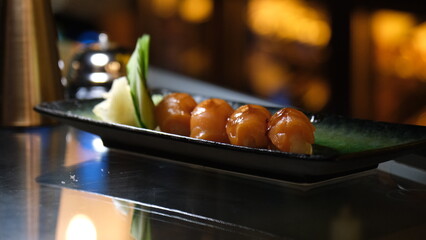 Sake nigiri dish in ceramic plate in dark interior