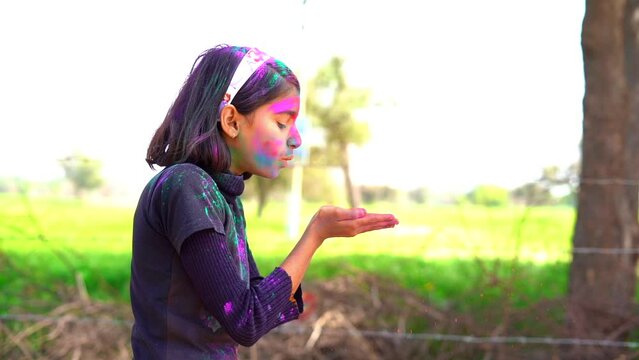Indian Little girl showing colourful palm and celebrating holi with colour splash