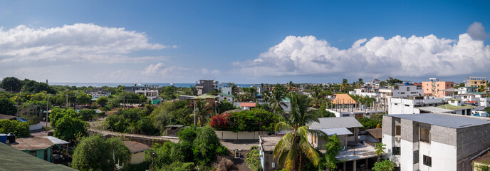 Panoramic view of the town of Santa Cruz in the Galapagos Islands. In the background you can see the sea and a sky with some clouds - obrazy, fototapety, plakaty