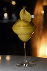 Frozen mabgo drink in a cocktail glass in front of a dark background in an illuminated interior
