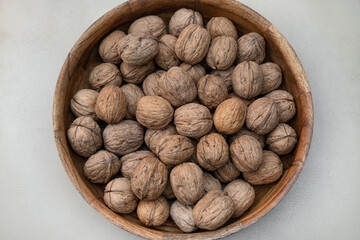 Big wooden bowl of whole walnuts in shells, delicious nutrient-dense nuts highly valued for their taste, health benefits and the culinary versatility, enjoyed on their own or in savory or sweet dishes