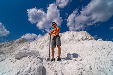 Man stands on white mountain with shovel in his hands