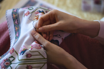 A woman hands embroidering flowers on a cloth. Close up view.