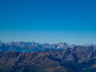 Fototapeta premium Panoramic view from majestic mountain peak of Hochschober, Schober Group, High Tauern National Park, East Tyrol, Austria. Wanderlust Austrian Alps in summer. Misty rugged ridges against clear blue sky