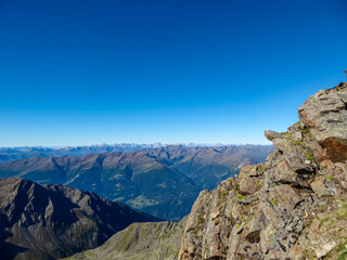 Panoramic view from majestic mountain peak of Hochschober, Schober Group, High Tauern National Park, East Tyrol, Austria. Wanderlust Austrian Alps in summer. Misty rugged ridges against clear blue sky