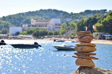 Balanced rock stack on a large, rough boulder on a beach on Skiathos island, Greece. Backdropped by...