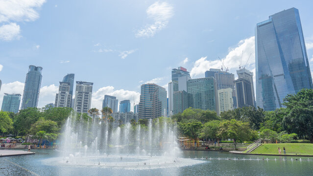 31 December 2023 in Malaysia A photo of a fountain dancing in a park. There is greenness among the trees amidst the large tall buildings in the heart of the city.