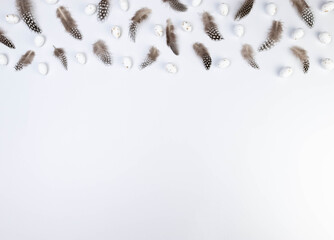 Top view of brown feathers, white easter eggs on white background. Creative easter composition, spring, copy space, flat lay. 