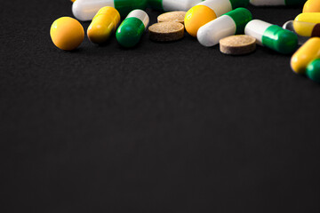 Medical pills. Color capsules medication. Black background. Health care concept. Free space for text. Medicines. Many different pills. Chemical industry.