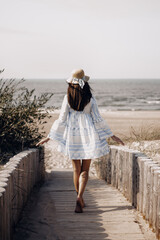 woman in hat walking to the beach
