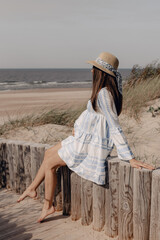 pregnant woman in hat sitting near the beach