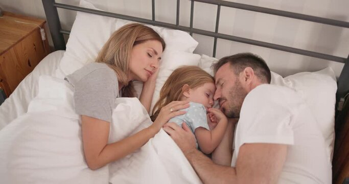 Adorable girl taking a nap with mom and dad