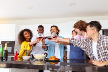 Multi-ethnic friends and family enjoy celebrating quality time together indoor.  People  raising...
