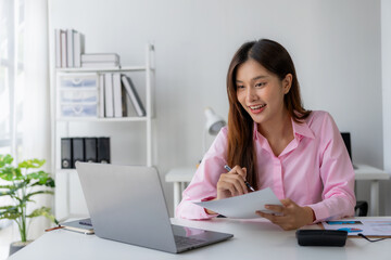 Annual summary report, laptop and paper placed at desk, Asian woman working online and planning financial data with laptop and succeeding with excited and happy face