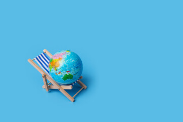 Beach lounger with globe, international holiday concepts, global relaxation, travel destinations, blue background