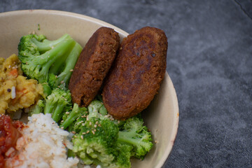 Vegan cutlets made of seitan. along with rice, kimchi, side veggies. Vegan bowl.
