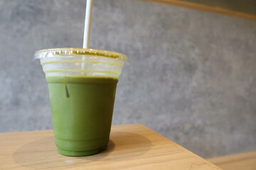 close up of green tea matcha lattee coffee drank a few slip with straw and on a wooden table with...