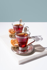 Dos tazas de té rojo con pasteles y dulces sobre mármol y fondo azul