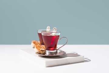 Dos tazas de té rojo con pasteles y dulces sobre mármol y fondo azul