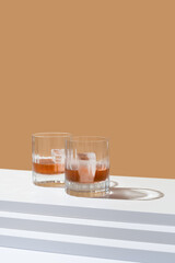 Dos vasos de whisky con hielo sobre un fondo marrón
