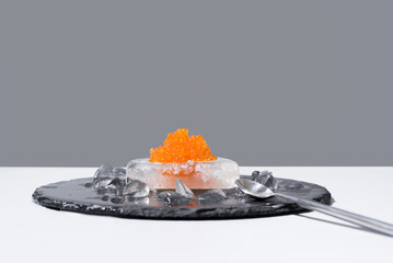 Caviar de salmón sobre hielo en un plato de pizarra. Comida gourmet sobre fondo gris