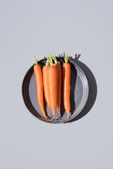 Zanahorias frescas crudas en un plato gris. Vista superior