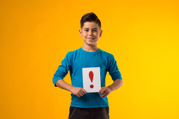 Kid boy holding exclamation point card. Education and curiosity concept