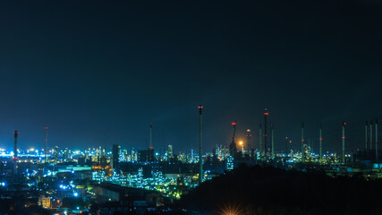 Fototapeta premium Panorama night cityscape and oil refinery, petroleum oil yard, tank storage field. Crude oil, natural gas. Nice lighting cover the city. Business and industrail, import and export, international 