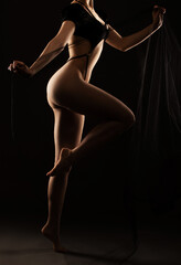 Obraz premium Beautiful girl body with black sexy underwear on a black background. A young sensual slender girl close up nudity.