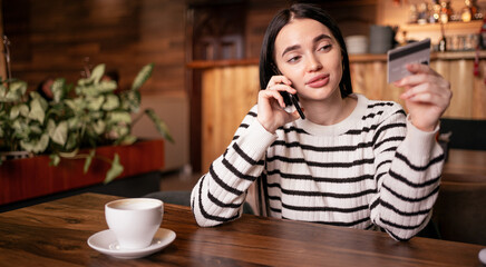 Beautiful woman using credit card for purchasing and shopping online on smartphone while sitting in the cafe