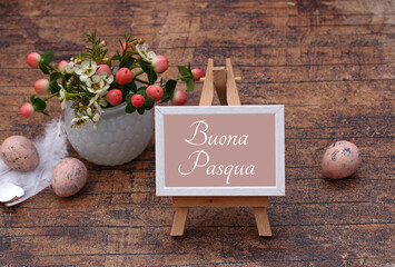 Il testo Buona Pasqua scritto su un cavalletto con decorazioni pasquali e fiori.