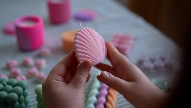Close-up cropped shot of unrecognizable young woman holding finished candle sitting at table. Process of making handmade natural scented candle. Creative occupation of making trendy diy candles.