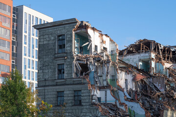 Old collapsed building against the background of new multi-storey buildings