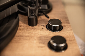 This is a detailed image of a section of a wooden turntable, focusing on its control knobs and part...