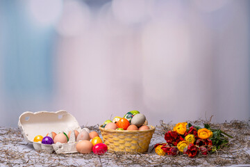 Obraz na płótnie Canvas Bunte Ostereier auf einem Tisch mit Bumenstrauß als Postkartenmotiv zu Ostern