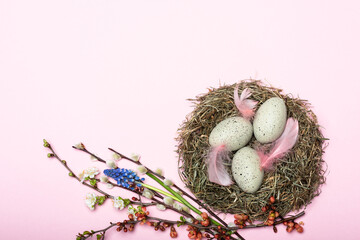 Nest mit gepunkteten Ostereiern und Blütendekoration vor pinkem Hintergrund