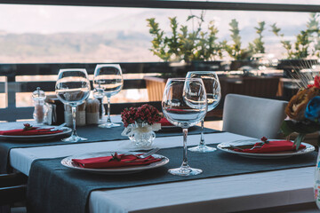 A restaurant table with a wine glass, cafe, cafe interior, stylish chandelier inside the cafe, vase in a luxurious space, stylish tables in the cafe, flowers