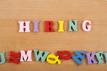 HIRING word on wooden background composed from colorful abc alphabet block wooden letters, copy...