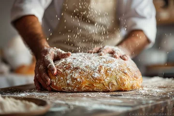 Poster An artisan baker carefully dusts a loaf of freshly baked bread with flour, highlighting the craft of traditional baking. © Fay Melronna 