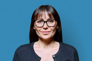 Portrait of serious middle aged woman with on blue background