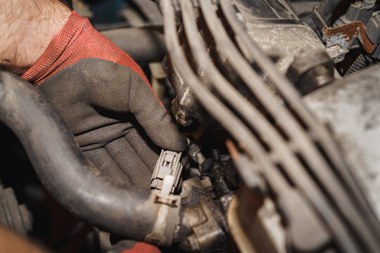 The mechanic is showing the lambda sensor connector in his hand. Auto service. Car repairing.