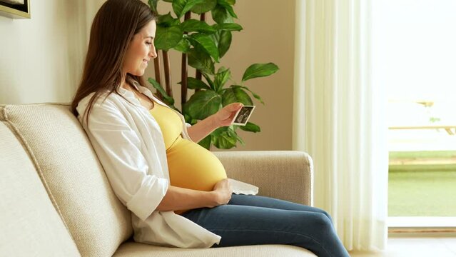 Pregnant woman looking at sonogram at home and looking happy