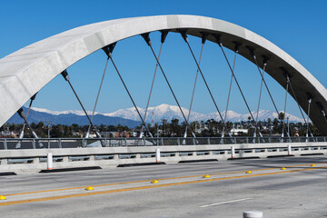 Los Angeles 6th Street Bridge arch with snow capped Mt Baldy and the San Gabriel Mountains in the...