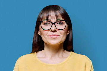 Headshot portrait of serious mature woman on blue background