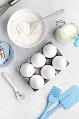 Baking ingredients: flour, eggs, yolk, on a white table.
