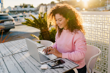 woman sitting in summer cafe working on laptop